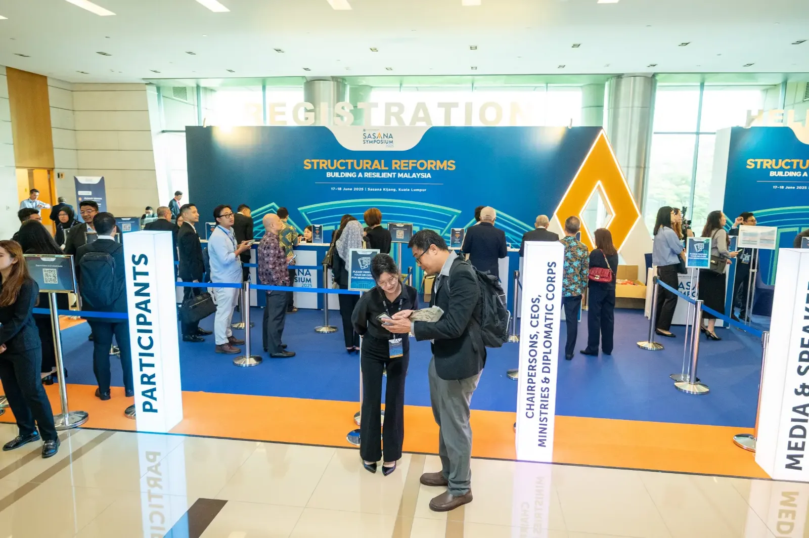 Wide view of a busy conference registration hall with participant lanes
